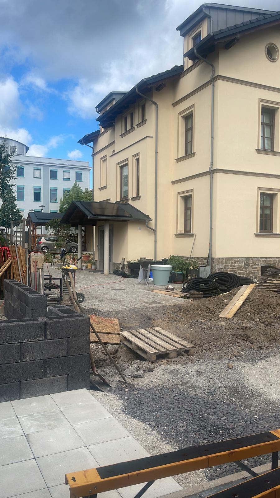 Vorbereiteter Untergrund und beginnende Mauerarbeiten in einer Außenanlage