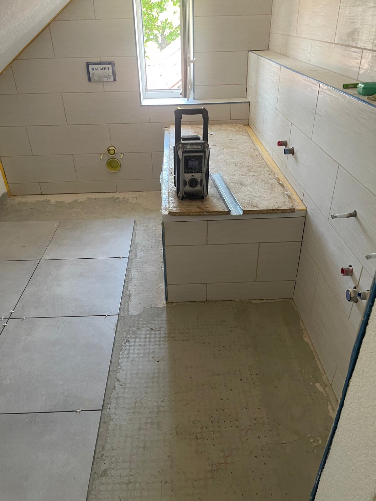 Beginnende Verlegung großformatiger Bodenfliesen in einem Badezimmer